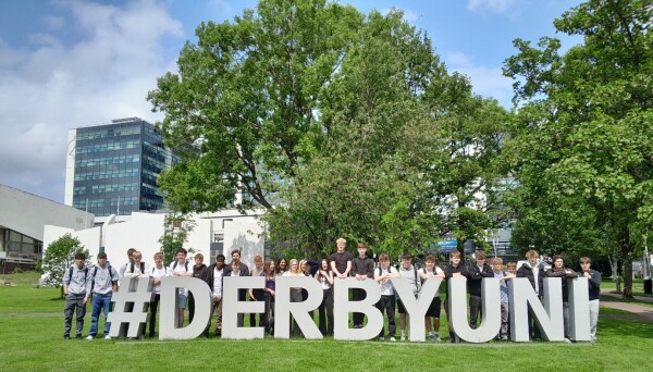 Students standing behind #Derby Uni sign 