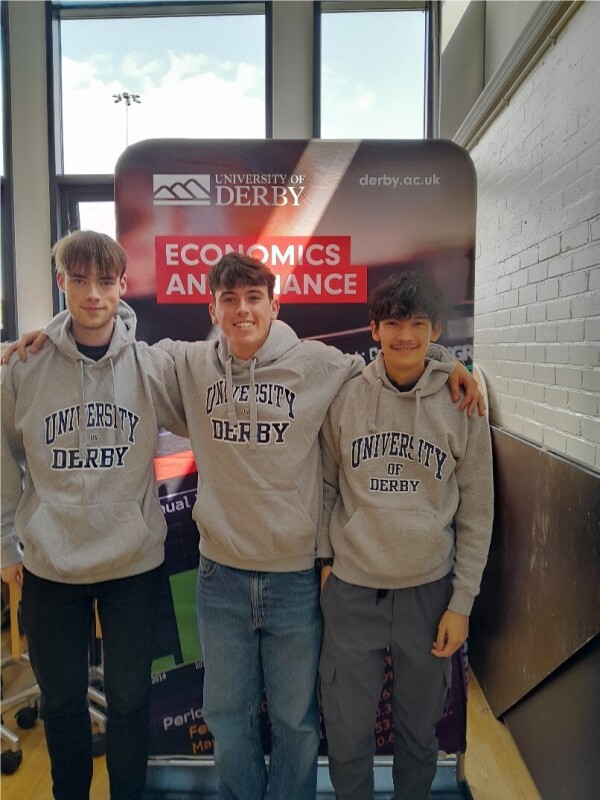 Three students wearing University of Derby jumpers 