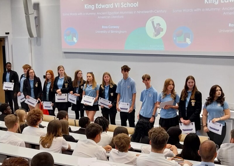Students standing in a lecture theatre with awards 